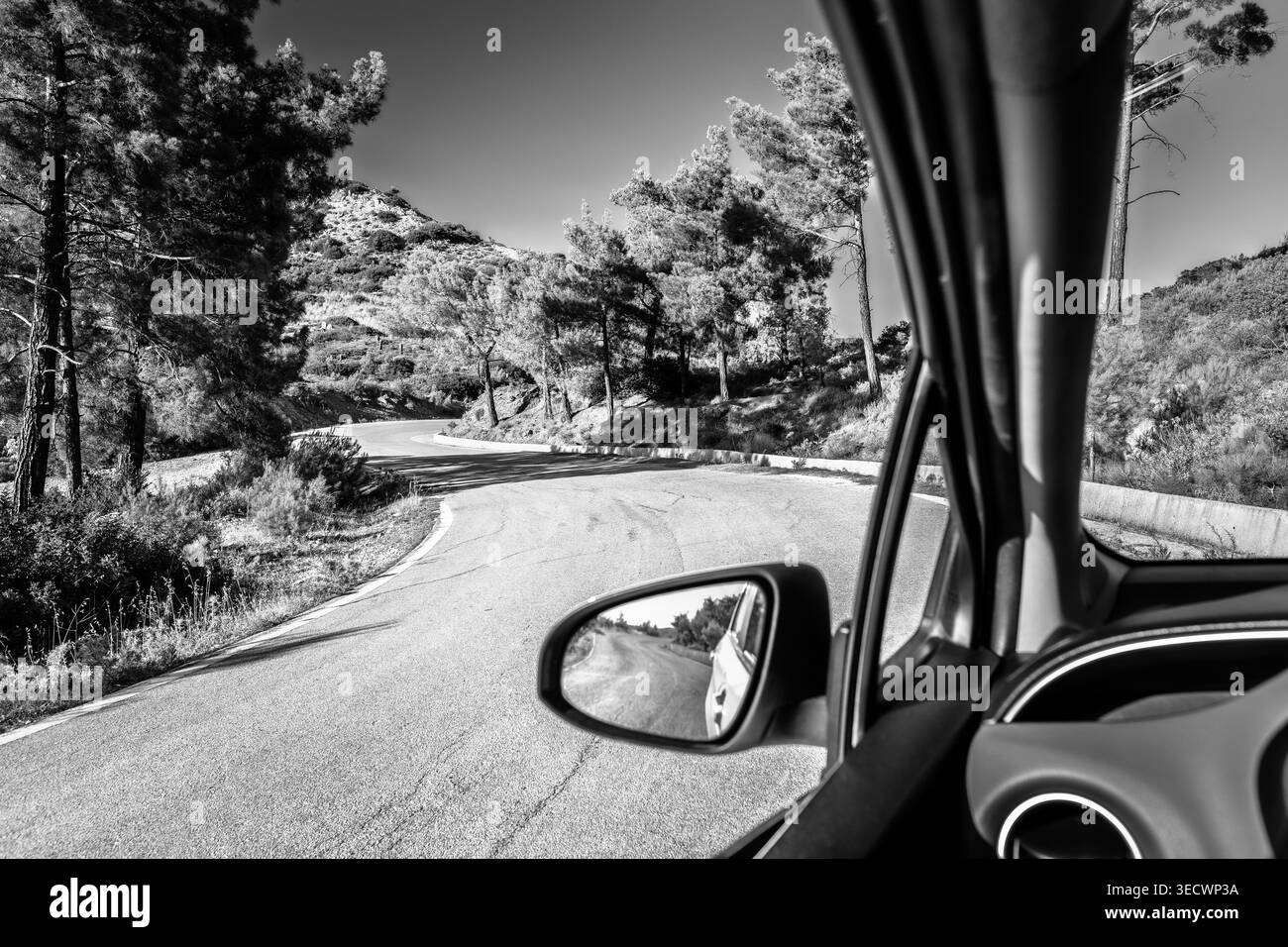 Rodi, Grecia: Prospettiva interna da un veicolo passeggeri in movimento che naviga su una tortuosa strada di montagna lastricata circondata da pini. Include Foto Stock