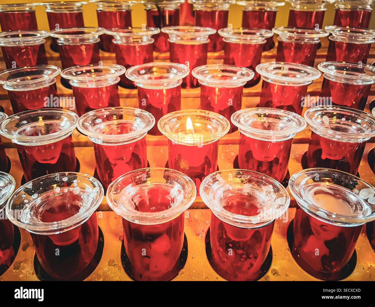 Una candela solitaria brucia in una chiesa in ricordo di una persona cara. Foto Stock
