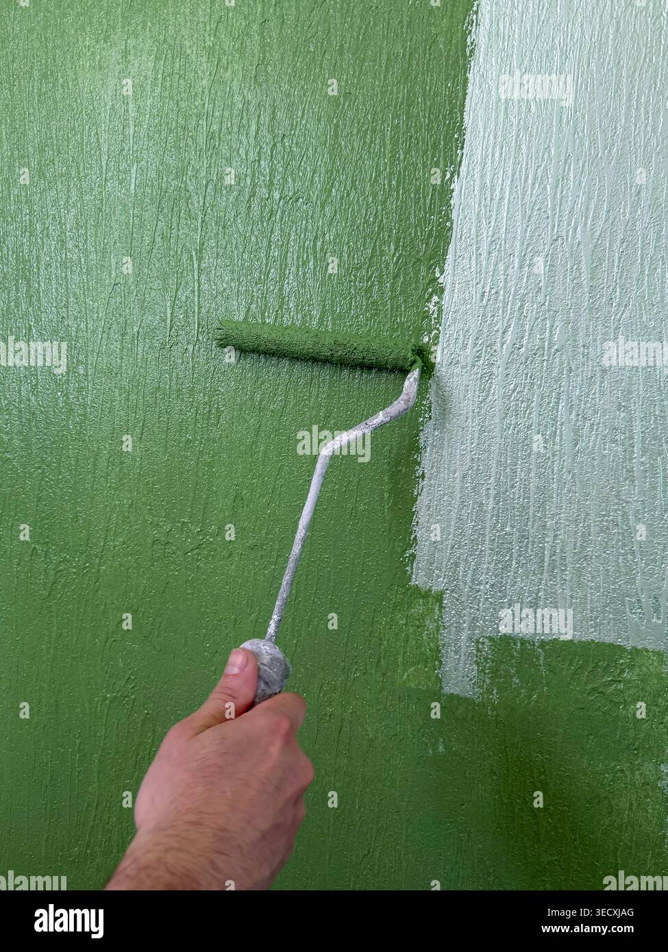 Strato finale spazzolato uniformemente sulla superficie della parete. Rivestimento della parete verde con uno strato uniforme di vernice Foto Stock