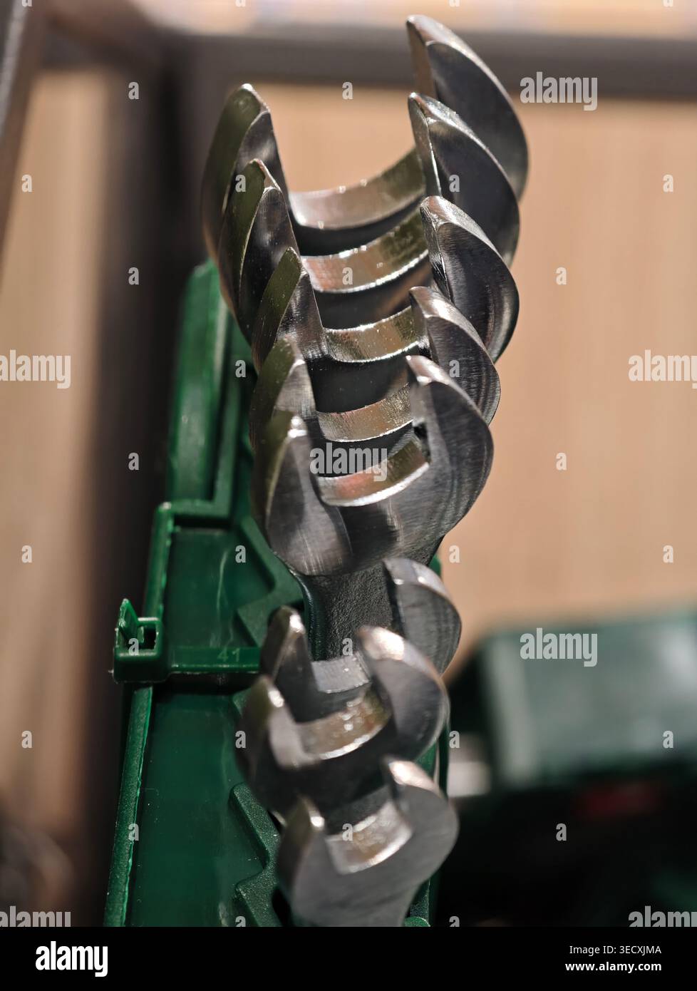 Le lame per trivella in metallo a spirale per primo piano rivelano superfici riflettenti lucide e contrassegni di lavorazione precisi impilati sul supporto verde con profondità ridotta Foto Stock