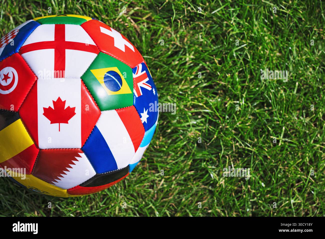 un pallone da calcio con varie bandiere nazionali sullo stadio. Concetto di competizione internazionale di calcio. Foto Stock