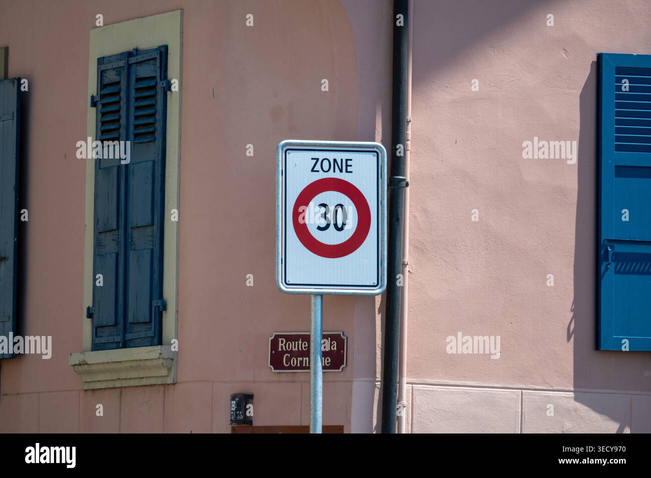 Segnaletica stradale della zona svizzera 30 e targa stradale su una facciata rosa con persiane blu, fotografata nella regione di Lavaux, Canton Vaud. Foto Stock