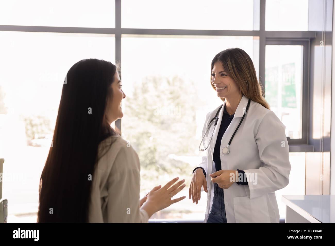 Giovane medico e paziente che ha una conversazione amichevole in clinica Foto Stock