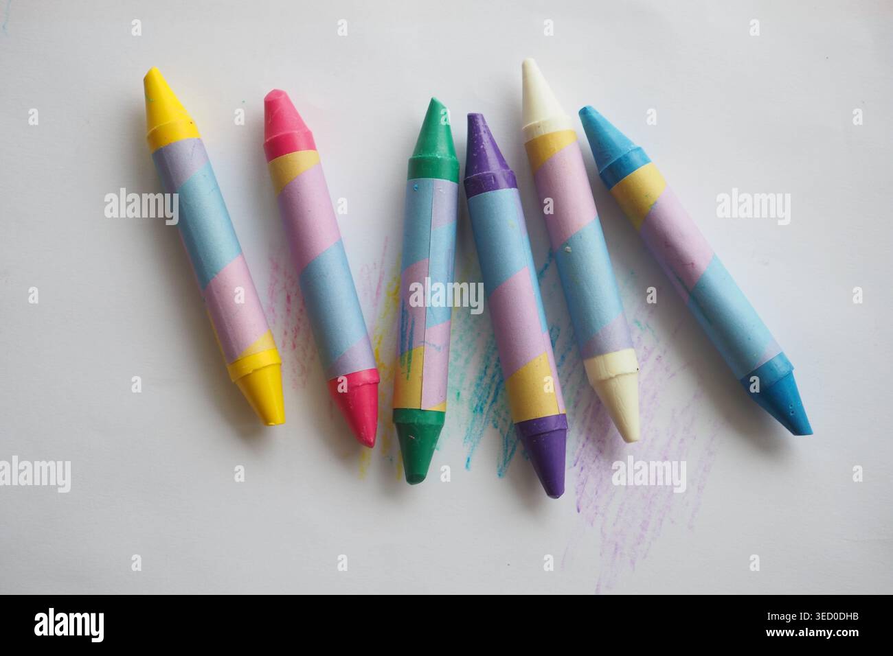 Pastelli colorati disposti su una superficie bianca per disegnare Foto Stock