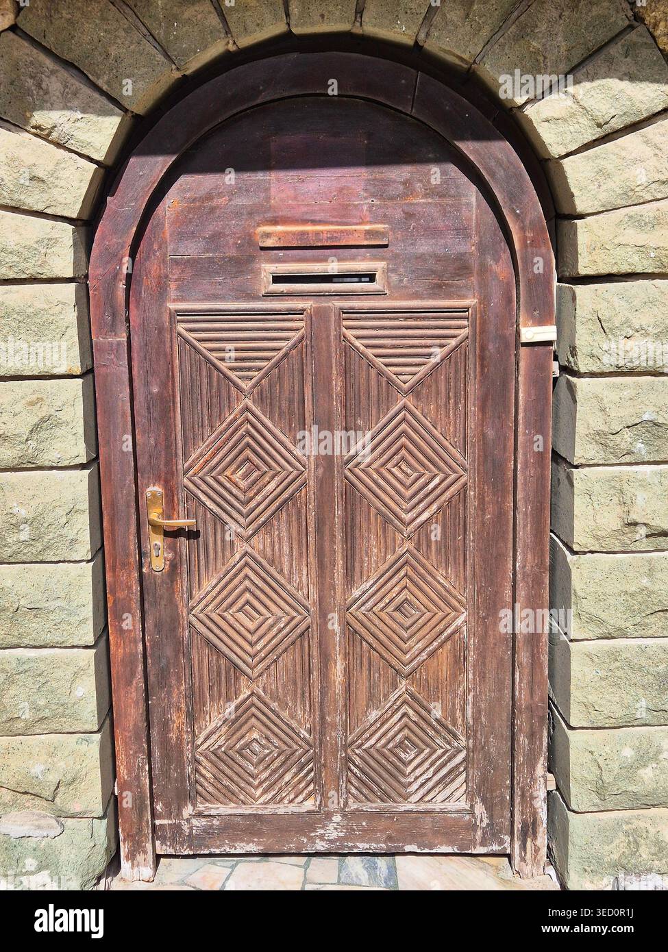 Massicce porte in legno con intagli geometrici spesso a forma di diamanti sono una caratteristica del risveglio bulgaro e dell'arco tradizionale - Immagine stock catturata con smartphone