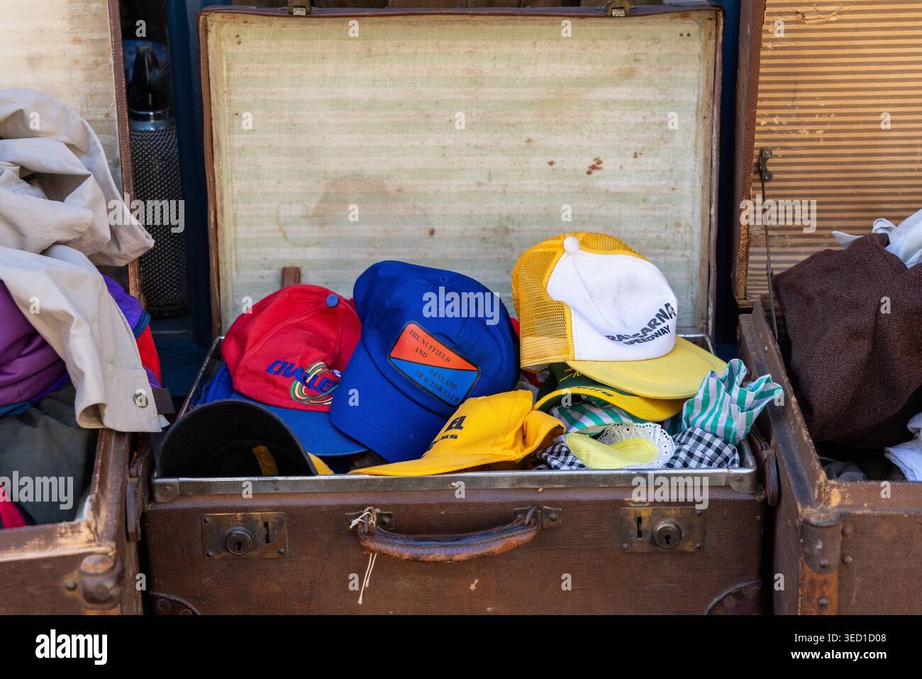 Valigia vintage aperta piena di vecchi cappellini da baseball fuori da un negozio in Inghilterra, Regno Unito Foto Stock