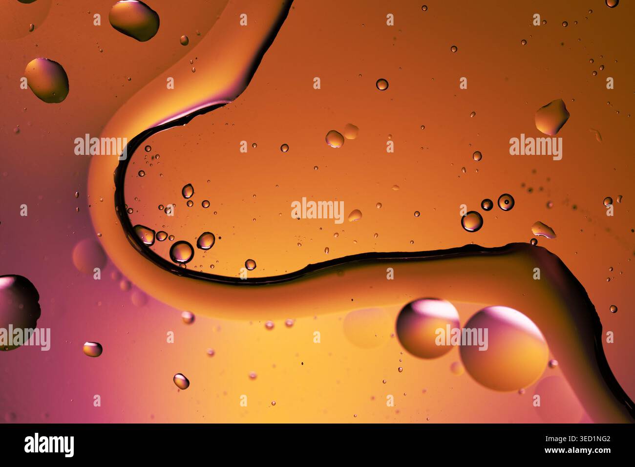 Una curva di liquido spazza separa i campi magenta e ambra con microbolle sparse Foto Stock