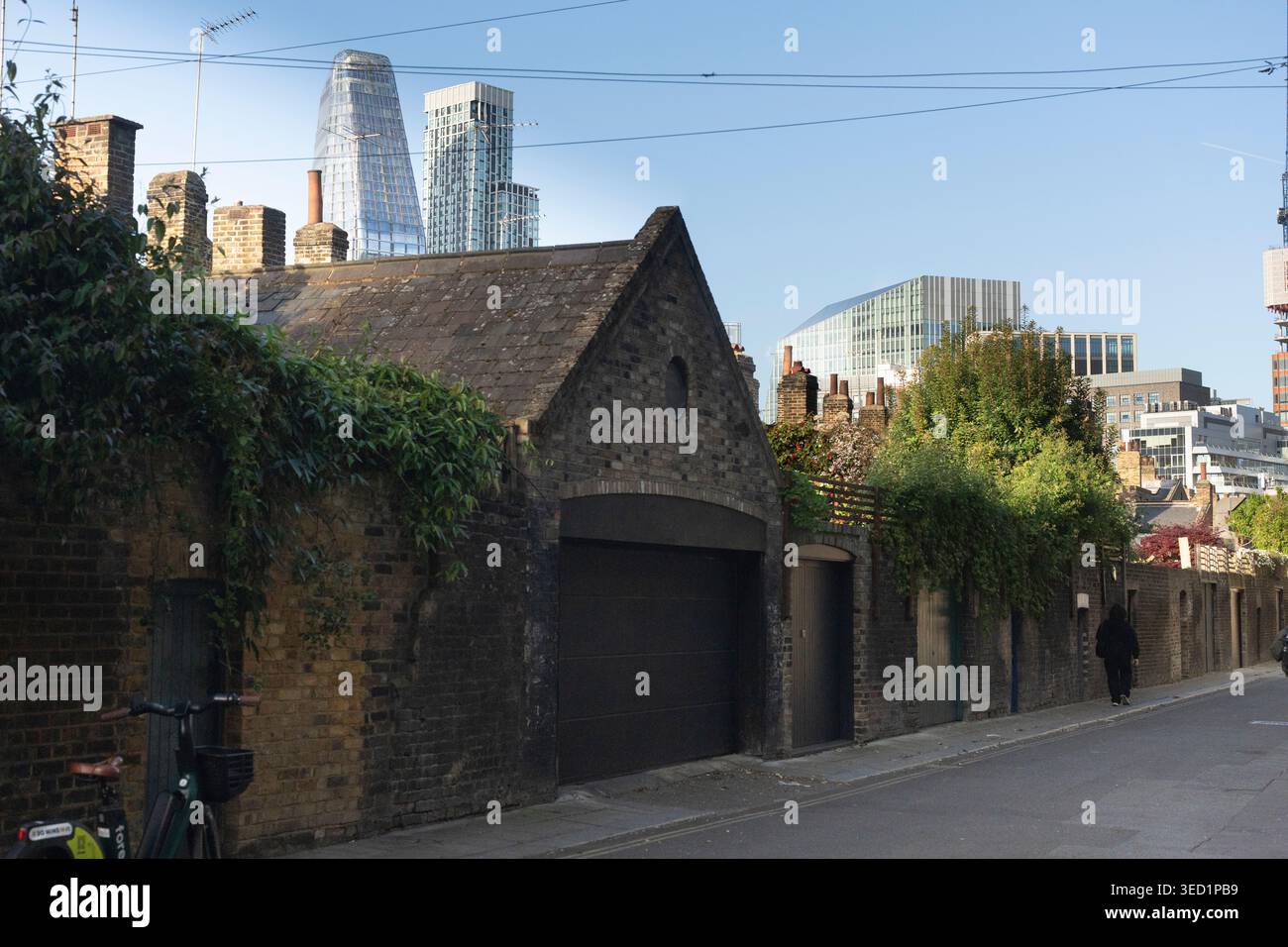 Una persona cammina davanti ai vecchi garage di Waterloo Brad Street a Londra, Roupell Street Foto Stock
