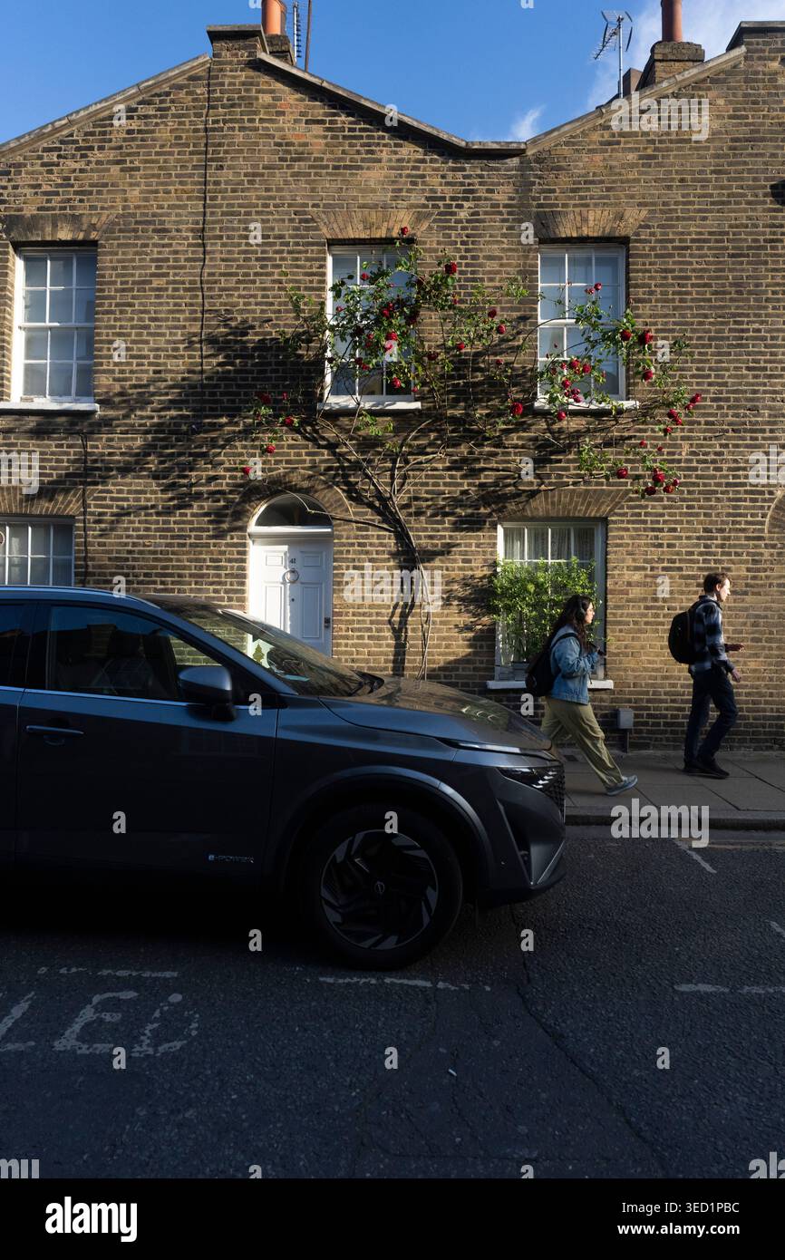 La gente passa davanti a una casa ricoperta di rose in una strada di Londra. Roupell Street Foto Stock