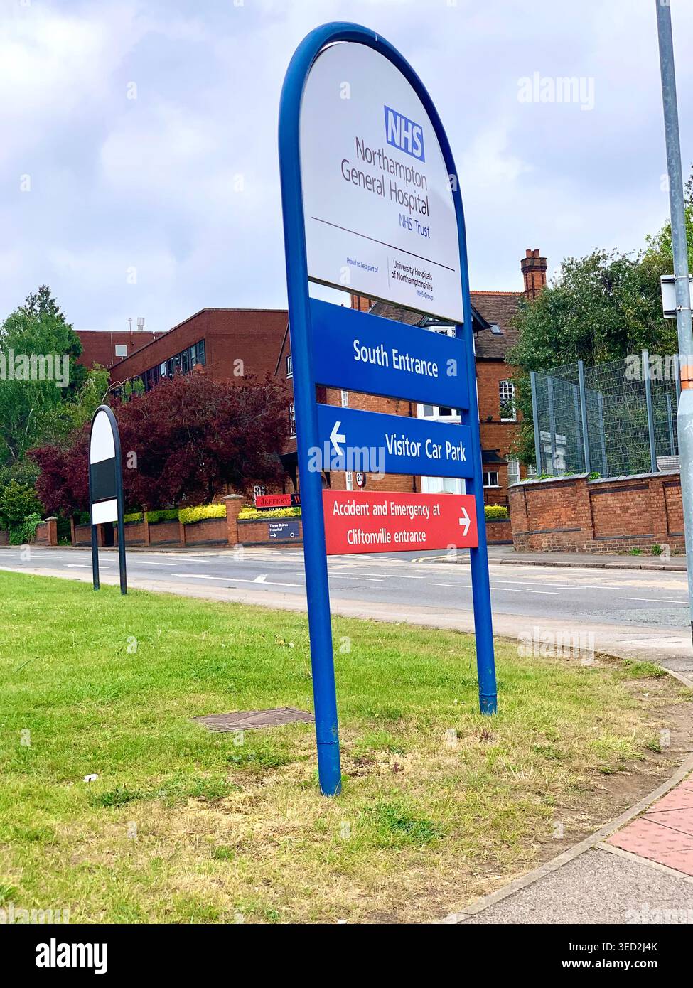 Vista esterna del Northampton General Hospital UK con visitatori e sedie a rotelle accesso visibile ingresso principale nuovo edificio zebra crossing - Immagine stock catturata con smartphone