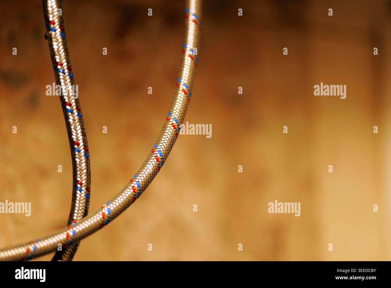 Viene mostrato un tubo flessibile dell'acqua intrecciato in acciaio inox con filettature di identificazione rosse e blu, utilizzato per il collegamento di impianti idraulici domestici come Foto Stock