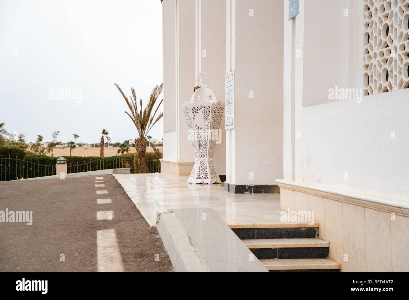 Fanosa lanterna Ramadan in metallo decorativo collocata all'ingresso della moschea vicino a scalini e pareti ad arco della facciata. Elemento di illuminazione islamico e decorazioni natalizie. Foto Stock
