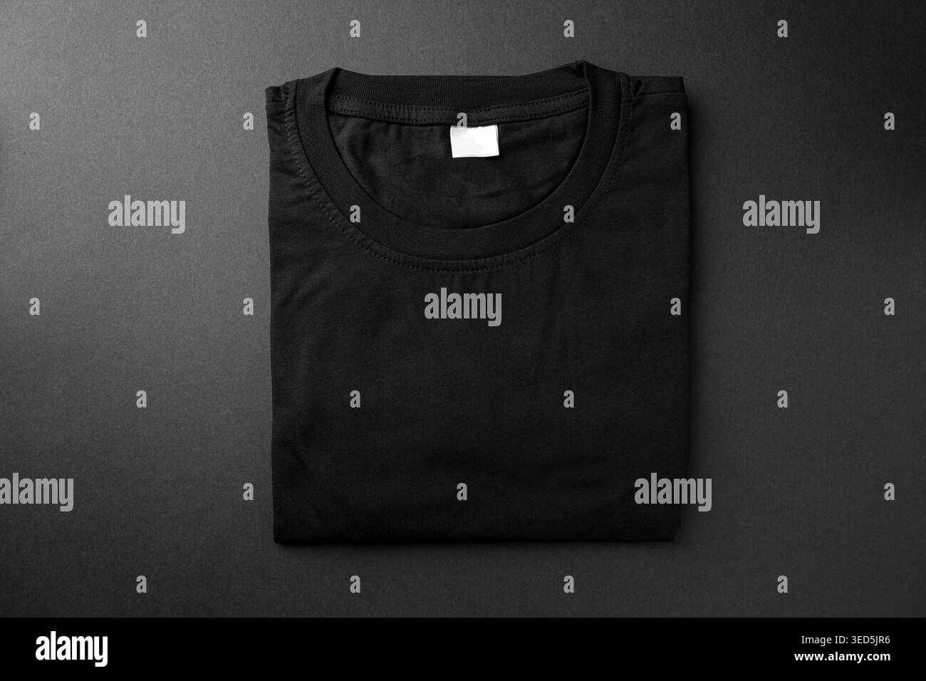 T-shirt nera ripiegata su sfondo scuro per un mockup di abbigliamento Foto Stock