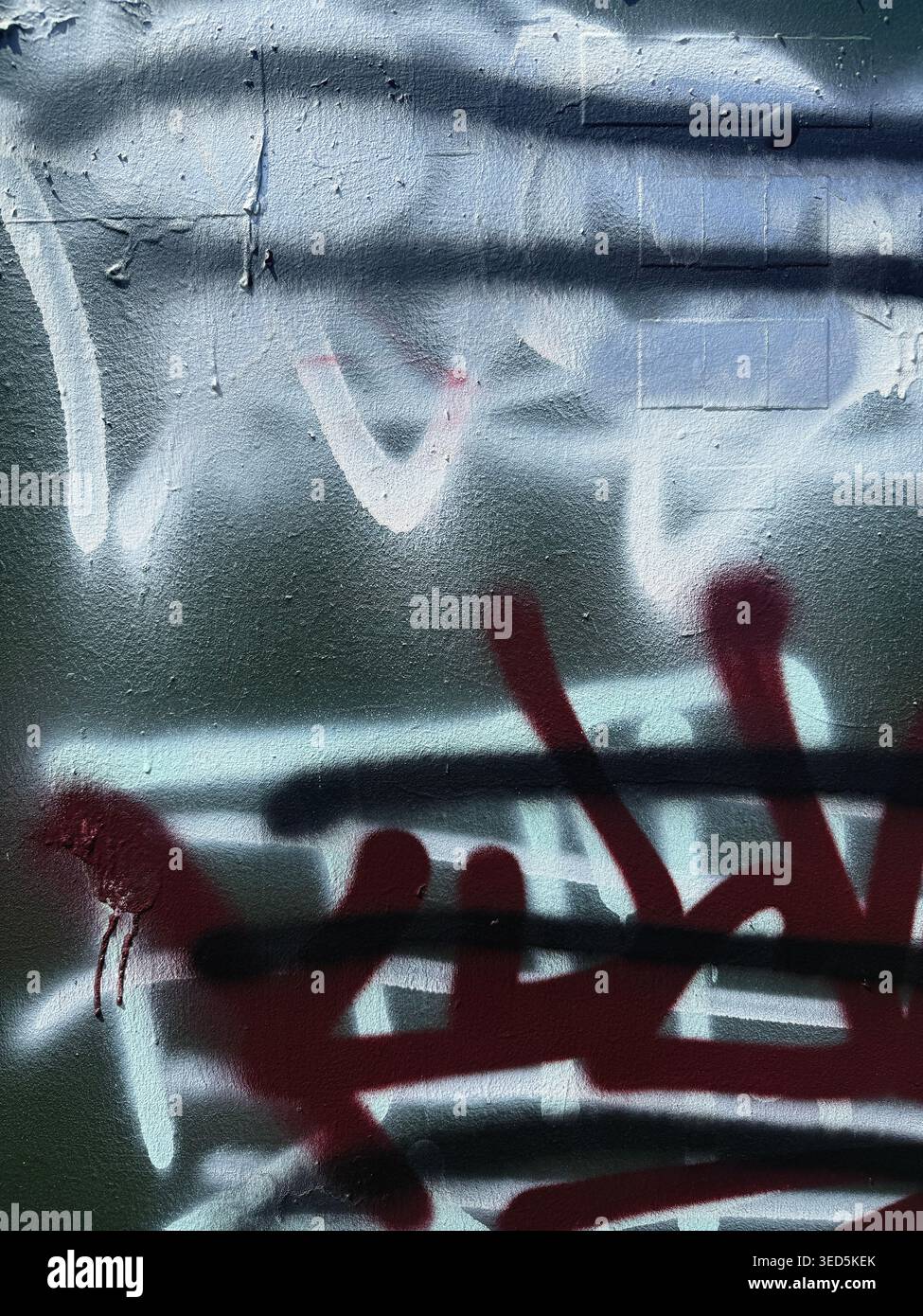 Vernice graffiti a strati su pareti in cemento, etichette spray rosse, nere e bianche, texture urbana grunge su sfondo verde - Immagine stock catturata con smartphone