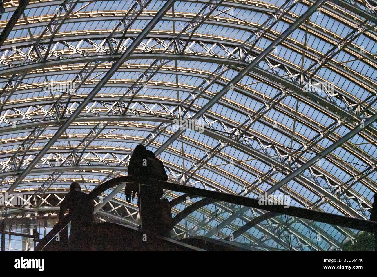 Vista ad angolo basso del tetto del capannone Victorian Barlow alla stazione internazionale di St Pancras, Londra, con sagome di persone su scala mobile. Foto Stock