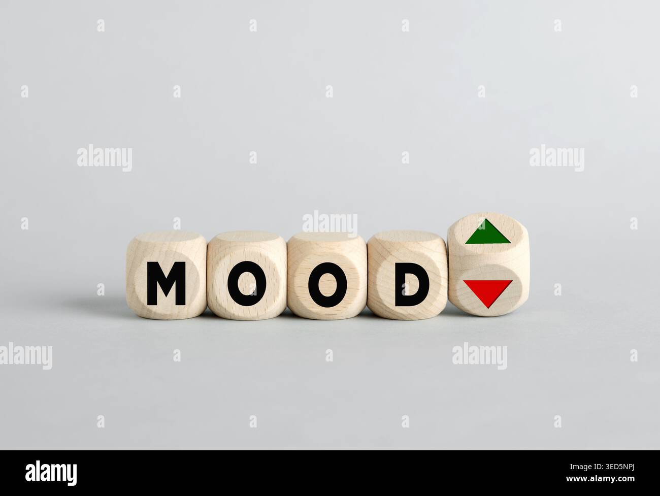 Quattro cubi di legno con lettere che compongono la parola "umore", con un quinto cubo che mostra frecce su e giù, raffiguranti sbalzi d'umore e instabilità emotiva Foto Stock