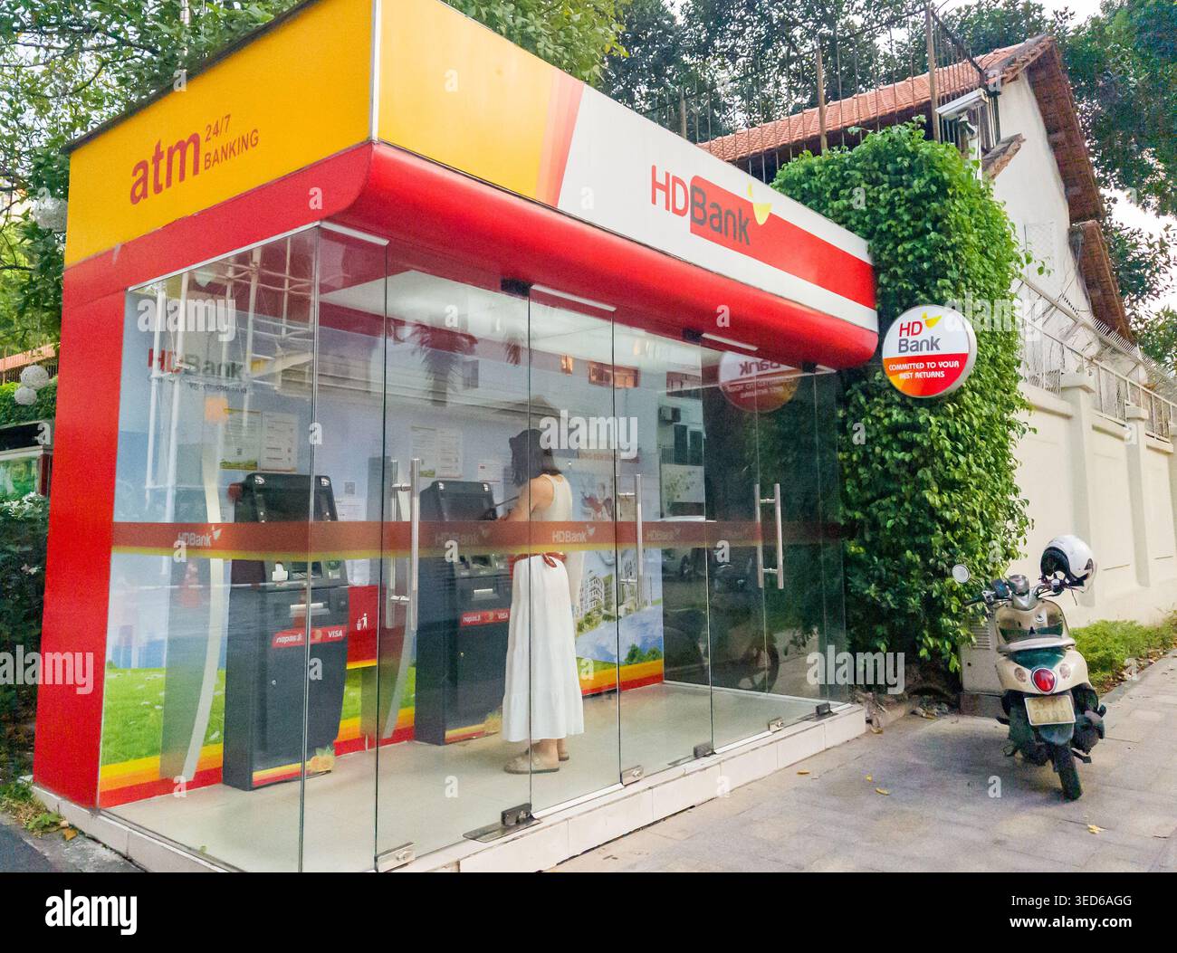 Chiosco ATM in vetro per HDBank all'aperto, l'individuo è visibile all'interno del chiosco, utilizzando una delle macchine. Ho chi Minh, Vietnam Foto Stock