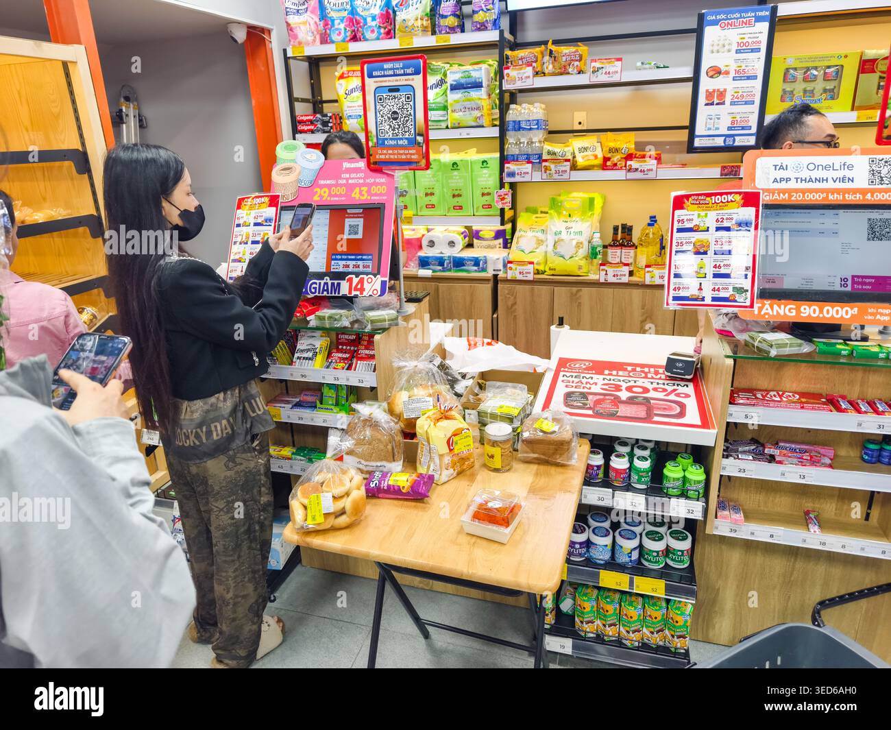 Gli acquirenti al momento del pagamento in un minimarket Kingfoodmart, che utilizza i telefoni cellulari per elaborare il pagamento scansionando il codice qr. Ho chi Minh, Vietnam Foto Stock