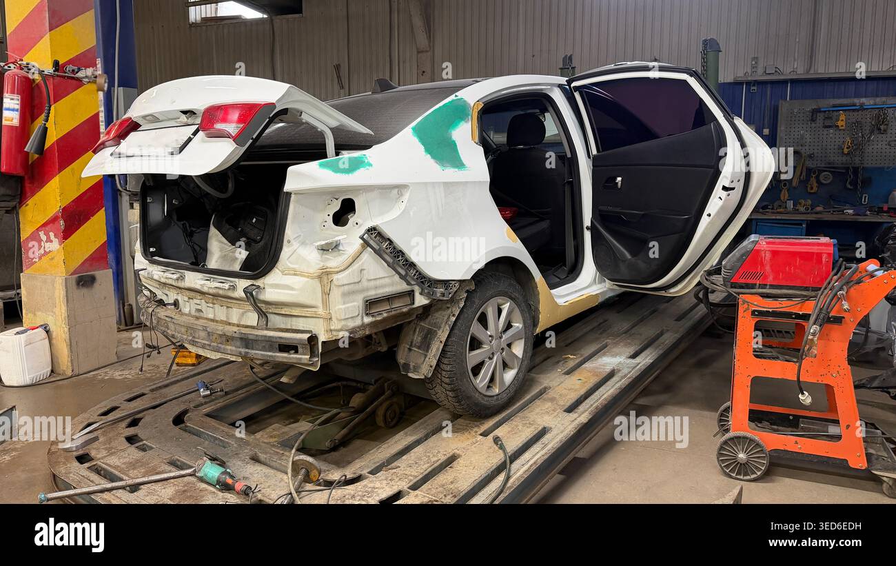 Auto con porte aperte in officina di riparazione auto durante il ripristino dopo l'incidente. Concetto di servizio industriale. Foto Stock