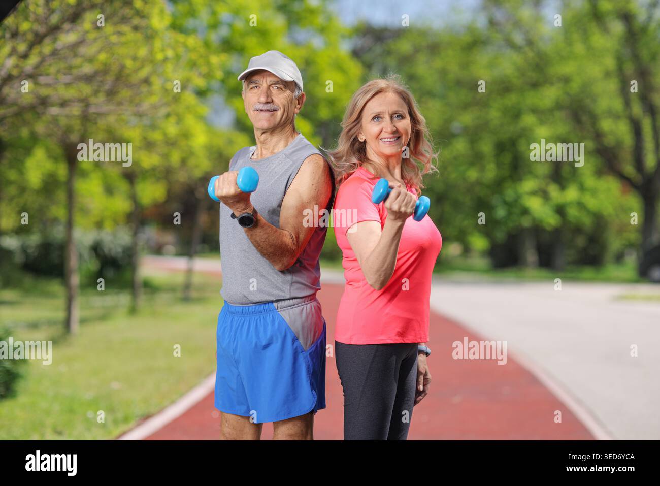 Coppia senior che si allenano con manubri in un parco Foto Stock