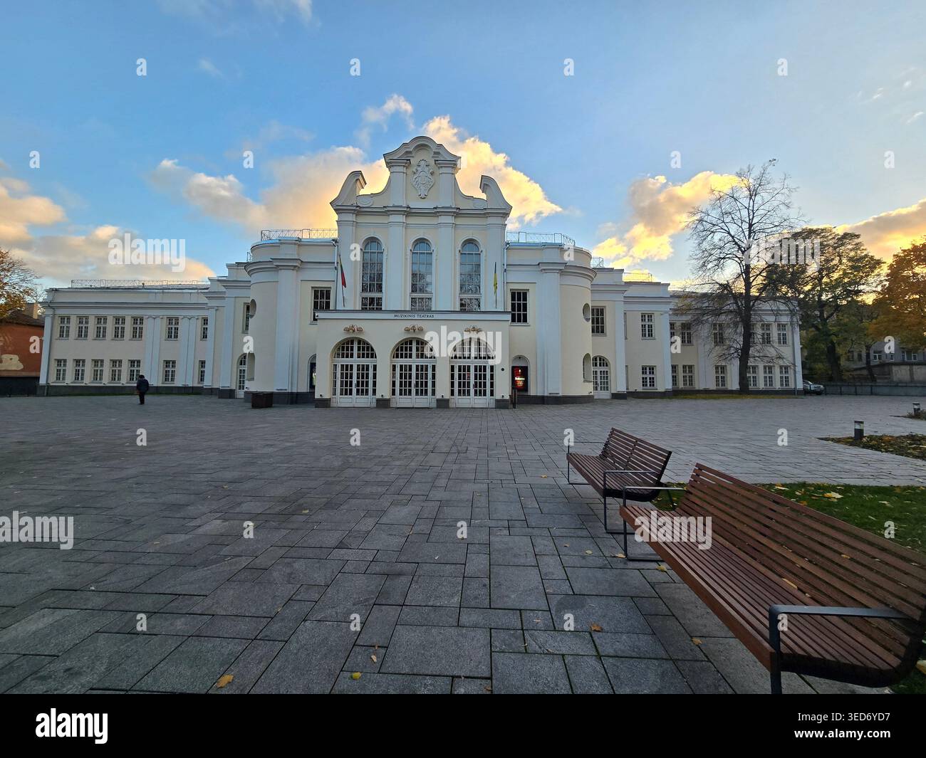 La facciata neoclassica del Kaunas State Musical Theatre con piazza lastricata e panchine in autunno, Kaunas, Lituania - Immagine stock catturata con smartphone