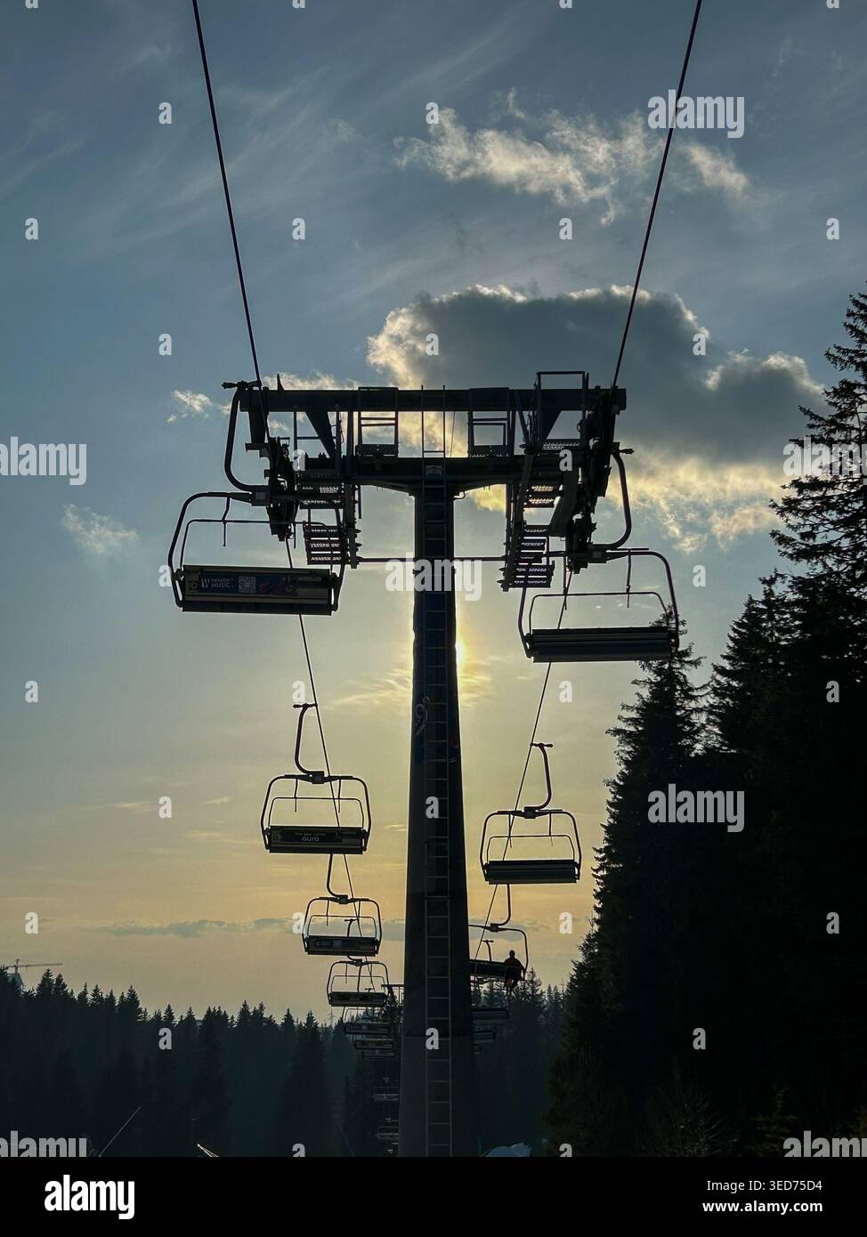 Sagoma della seggiovia sullo scintillante cielo del tramonto a Kopaonik, Serbia, con un paesaggio forestale e nuvole spettacolari. - Immagine stock catturata con smartphone