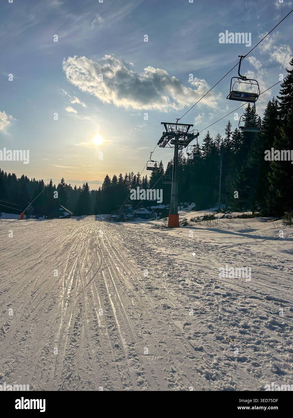 Pista da sci innevata con seggiovia sotto il sole luminoso a Kopaonik, Serbia, circondata dalla foresta e dal cielo invernale limpido. - Immagine stock catturata con smartphone