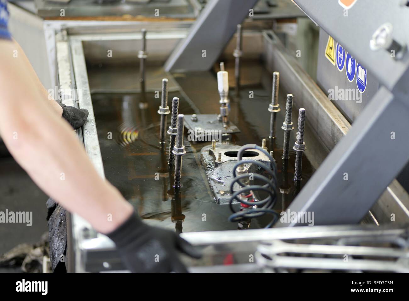 La prova di tenuta della testata nel serbatoio dell'acqua mostra un componente pressurizzato fissato con telaio metallico mentre il tecnico controlla la presenza di bolle d'aria che indicano incrinature. Foto Stock