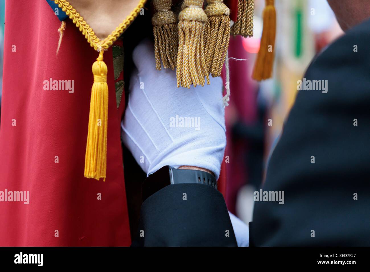 Dettaglio della mano con guanto bianco che regge una bandiera ornamentale con tazze dorate Foto Stock