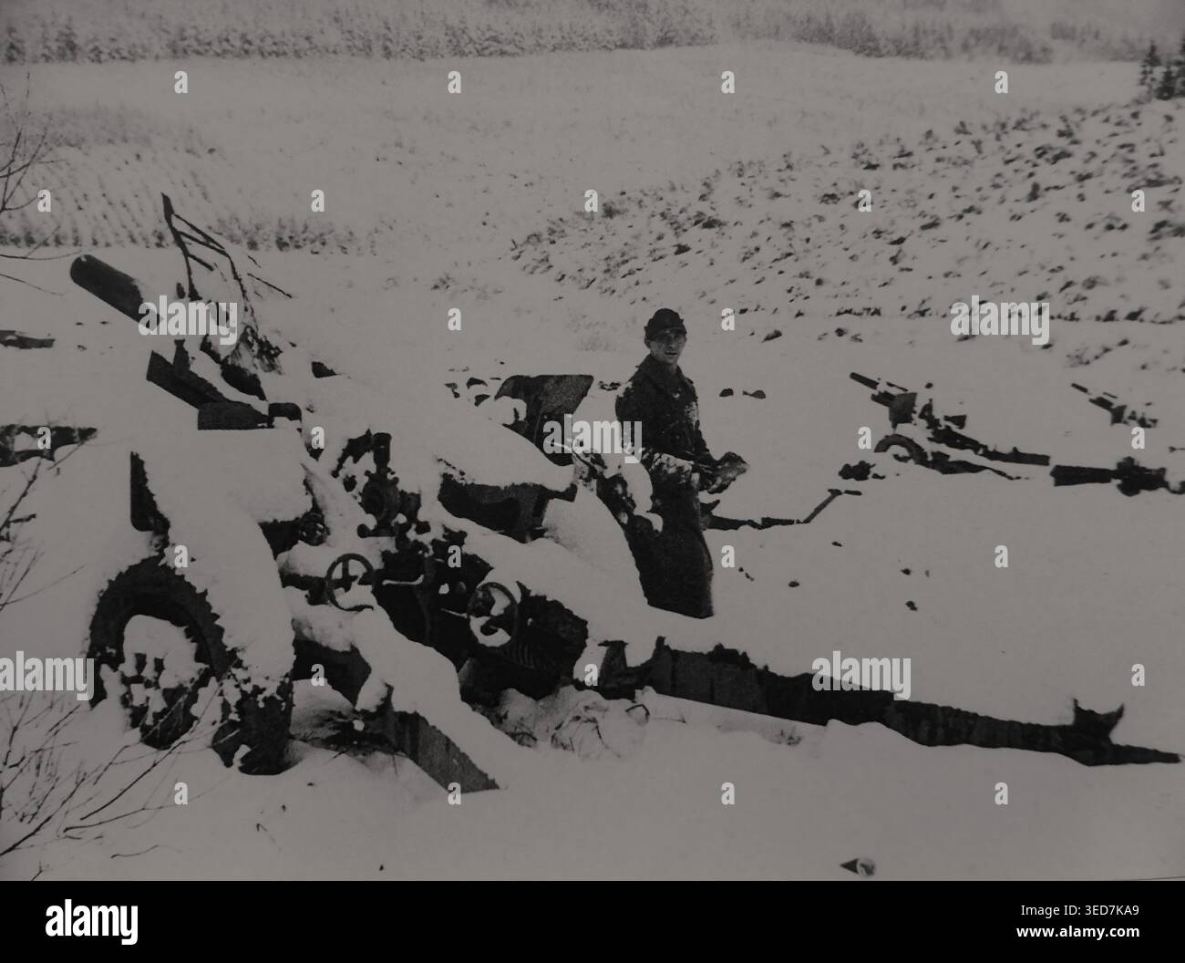 Soldato tedesco accanto ad una batteria di obici americani M-101 da 105 mm catturati nelle vicinanze di Saint-Vith dicembre 1944.   Documento storico, seconda guerra mondiale Foto Stock