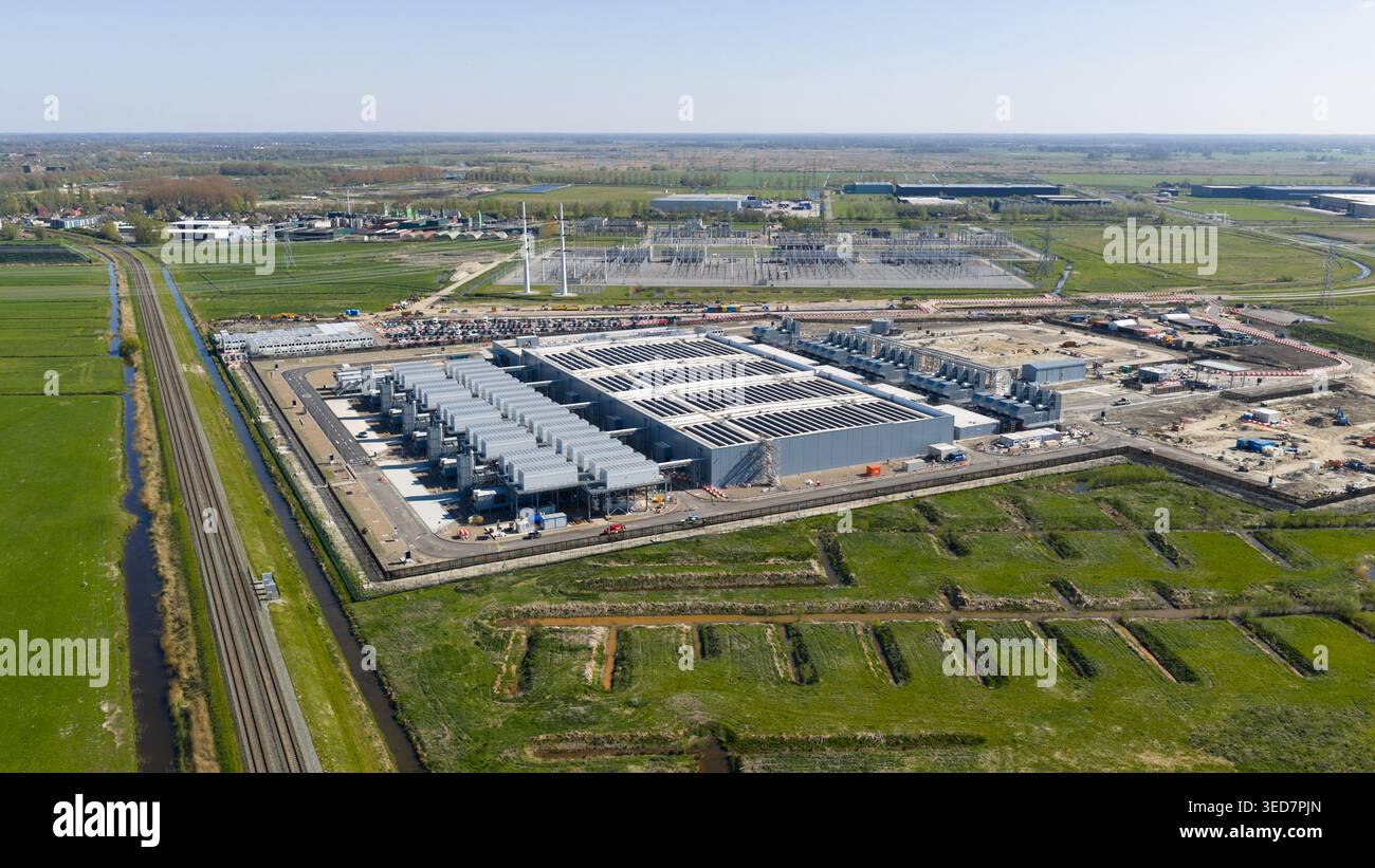 Veduta aerea del Datacenter Westpoort con grandi unità di raffreddamento industriali e campi verdi circostanti con un binario ferroviario a Groningen, Groningen Foto Stock