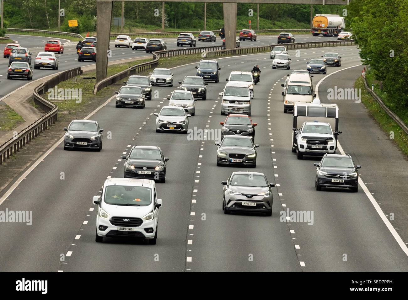 Auto e camion viaggiano lungo la M6 a nord di Warrington durante un movimentato pomeriggio, mostrando il ritmo della vita quotidiana su questa importante autostrada. Foto Stock