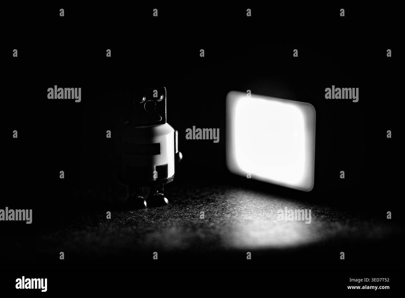 Robot bianco e nero sul simbolo del pannello illuminato, figura, giocattolo Foto Stock