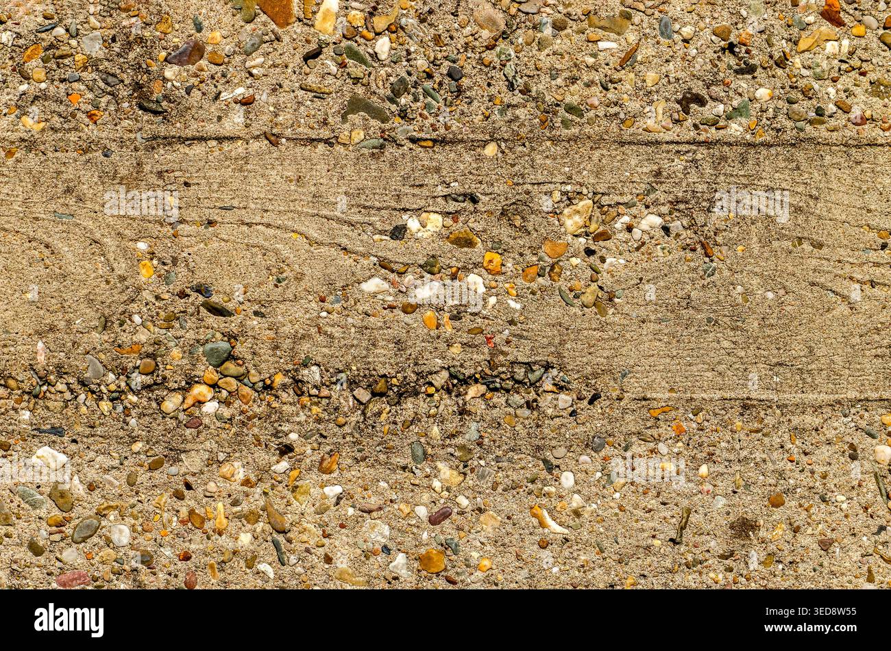 Parete di cemento ruvida e resistente agli agenti atmosferici in cui sono presenti piccoli ciottoli sulla superficie e su cui sono visibili le impronte della cassaforma Foto Stock