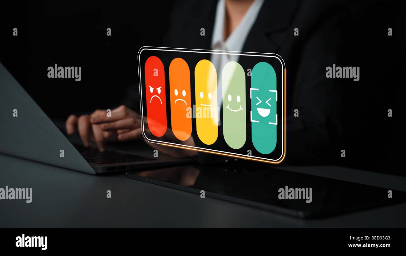 Professionista aziendale che utilizza un laptop con sistema olografico di feedback emozionale che visualizza varie espressioni facciali su sfondo scuro Gluon. Foto Stock