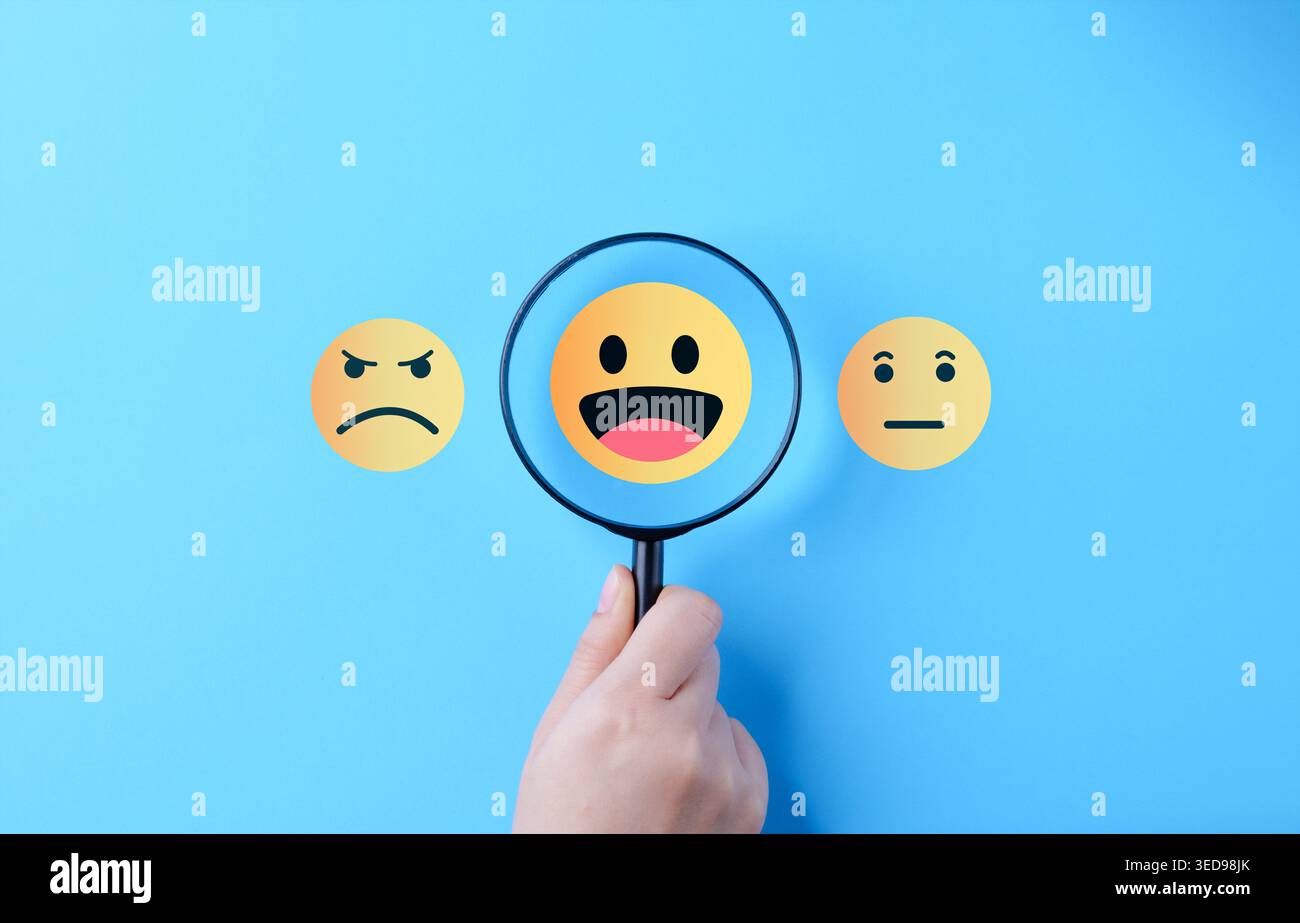 Sondaggio sulla soddisfazione dei clienti e concetto di feedback positivo. mano che tiene la lente d'ingrandimento sopra happy emoji, mostrando qualità del servizio, esperienza utente, Foto Stock