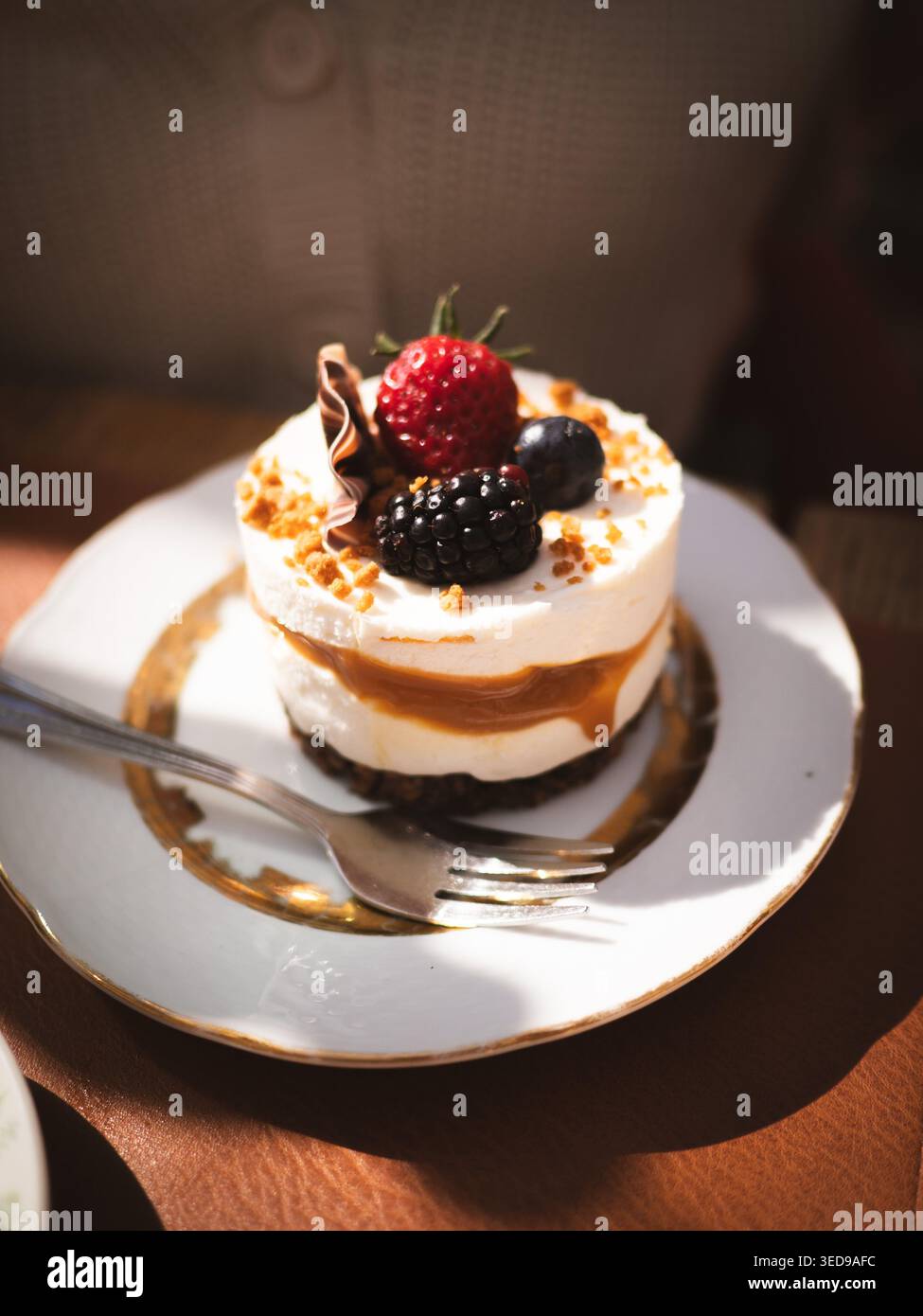 Mousse di caramello a strati condita con frutti di bosco freschi e ricci di cioccolato su piatto vintage presso Ott and Matilda Cafe, Estonia Foto Stock