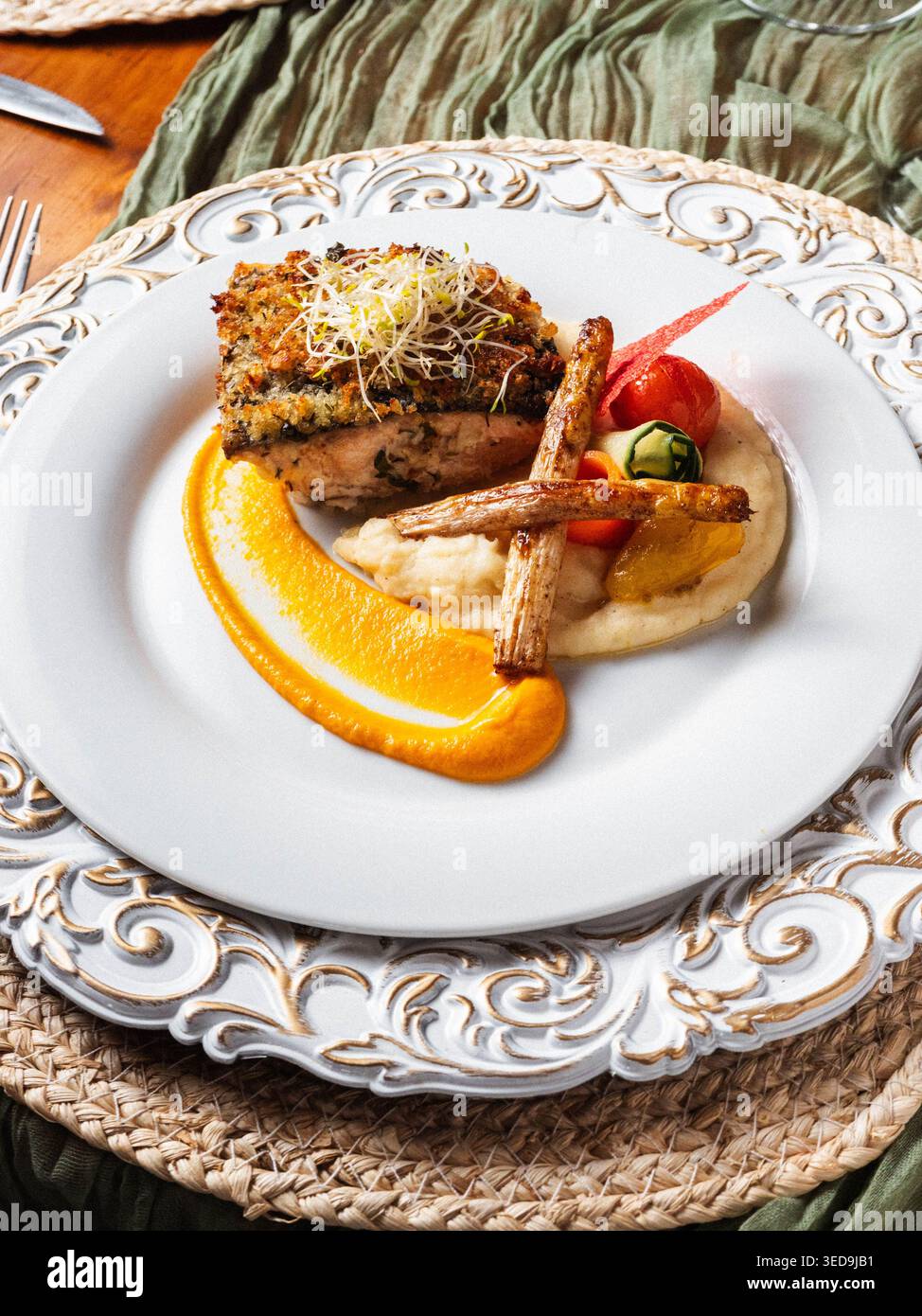 L'elegante piatto può contenere piatti ben placcati. La crosta dorata corona un tenero pezzo di proteina. La scorza d'arancia e la salsa cremosa aggiungono un contrasto vivace. Erbe fresche e. Foto Stock