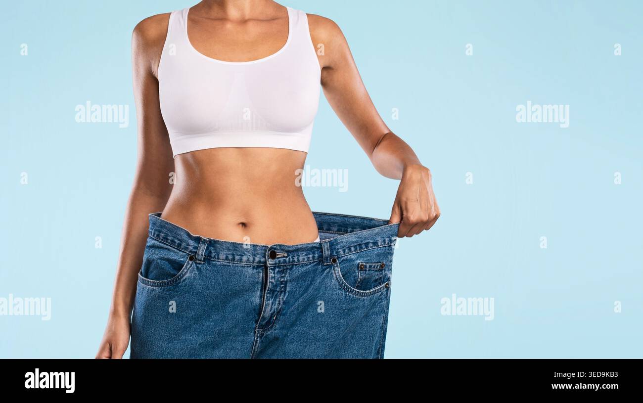 Primo piano di Donna tirando i suoi vecchi jeans larghi sciolti Foto Stock