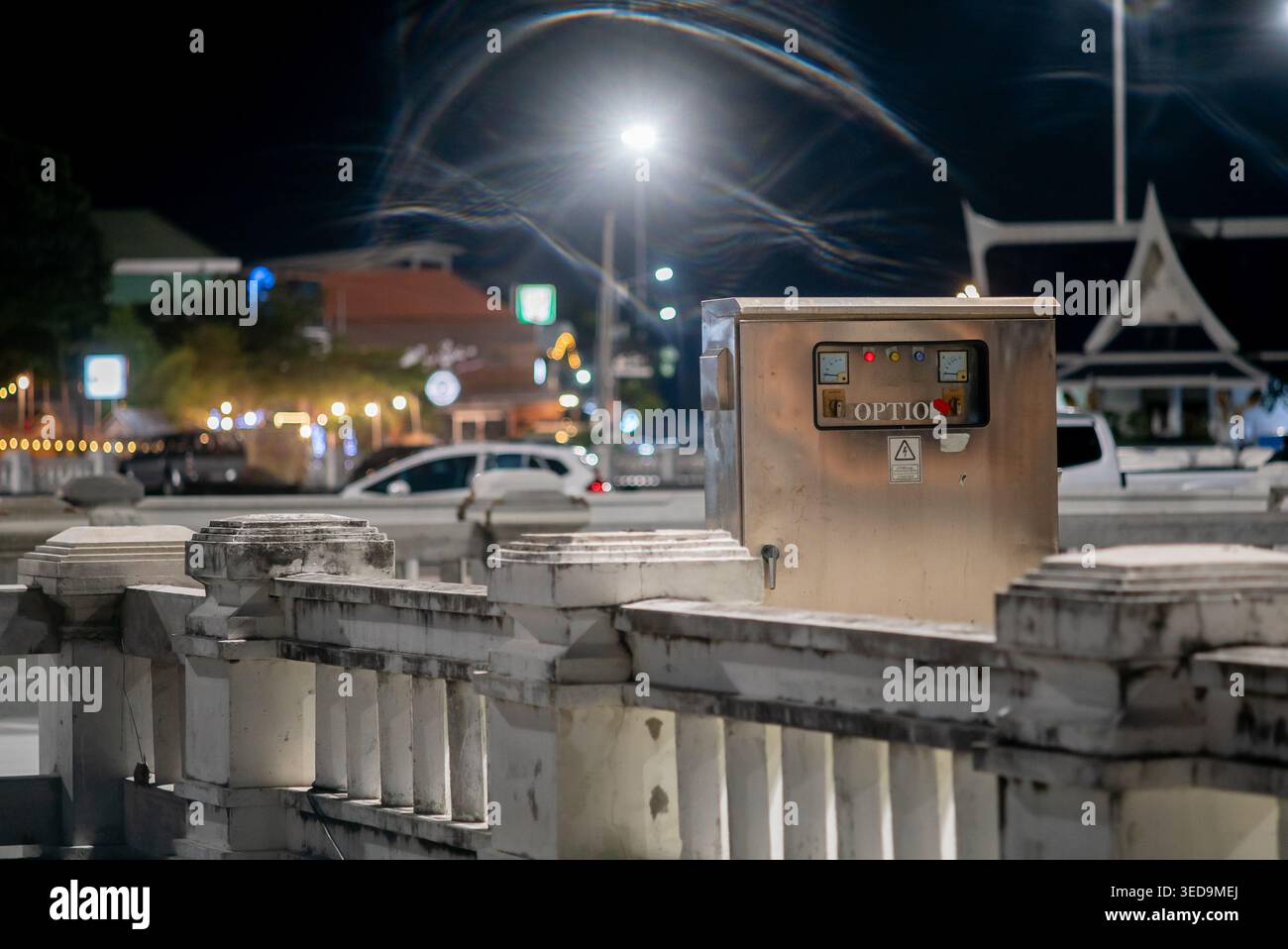 Una scatola metallica si erge in modo prominente su una strada della città di notte, circondata da architettura urbana e luci soffuse, creando un'atmosfera intrigante. Foto Stock