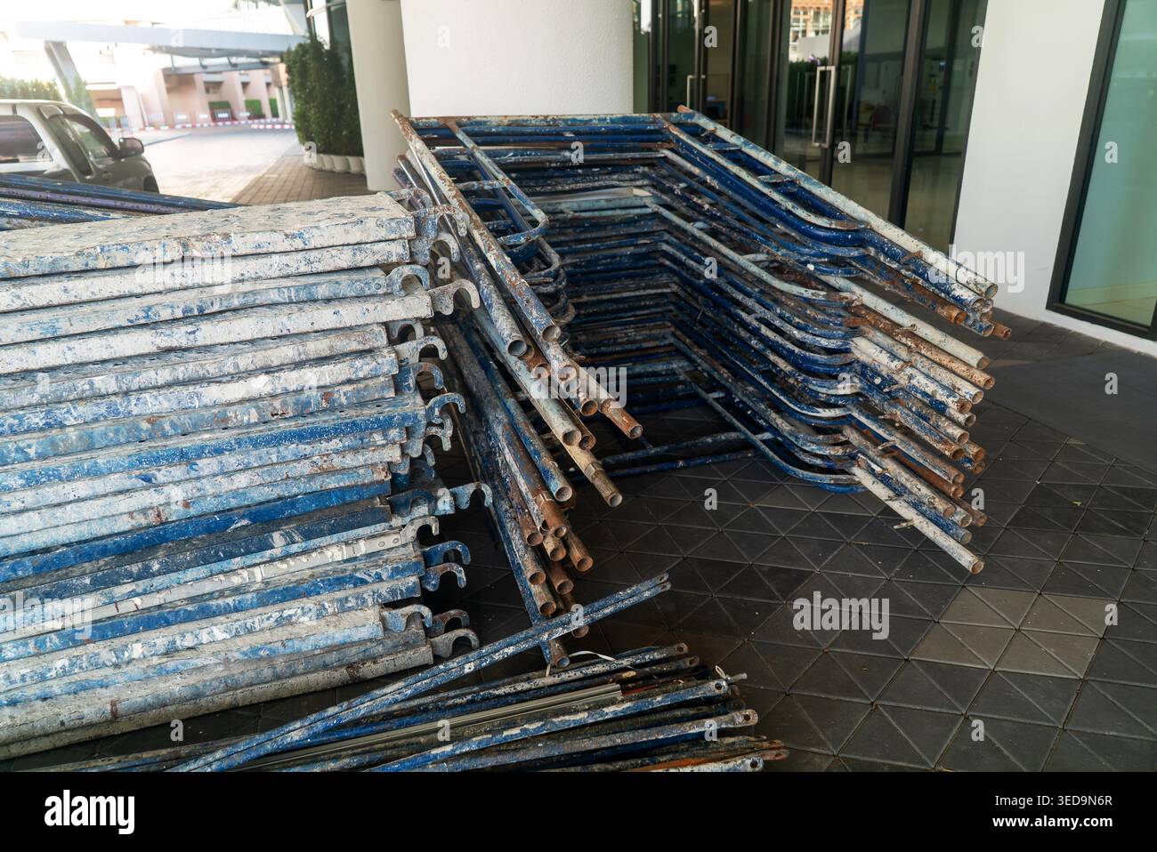 Un mucchio di tubi metallici per impalcature intemprati impilati all'aperto vicino a un cantiere edile. I materiali industriali mostrano il loro uso pratico in buildi Foto Stock
