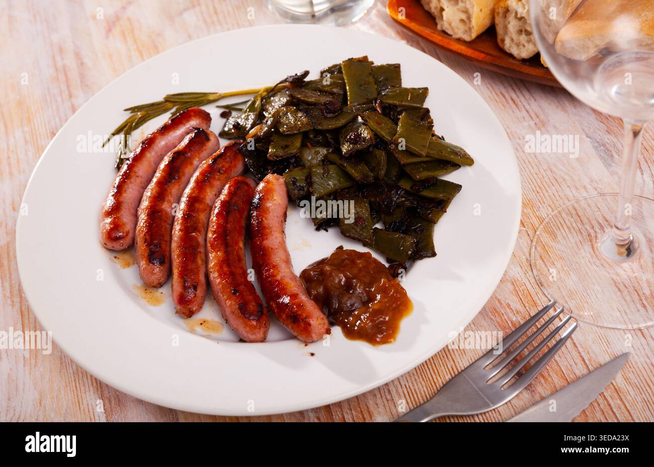 Salsicce fritte servite con fagioli verdi al piatto Foto Stock