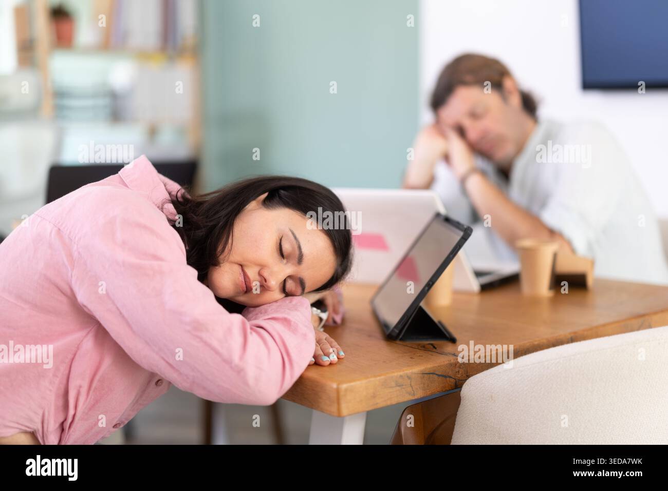 Donna di mezza età che dorme al tavolo dopo una lunga giornata di lavoro Foto Stock