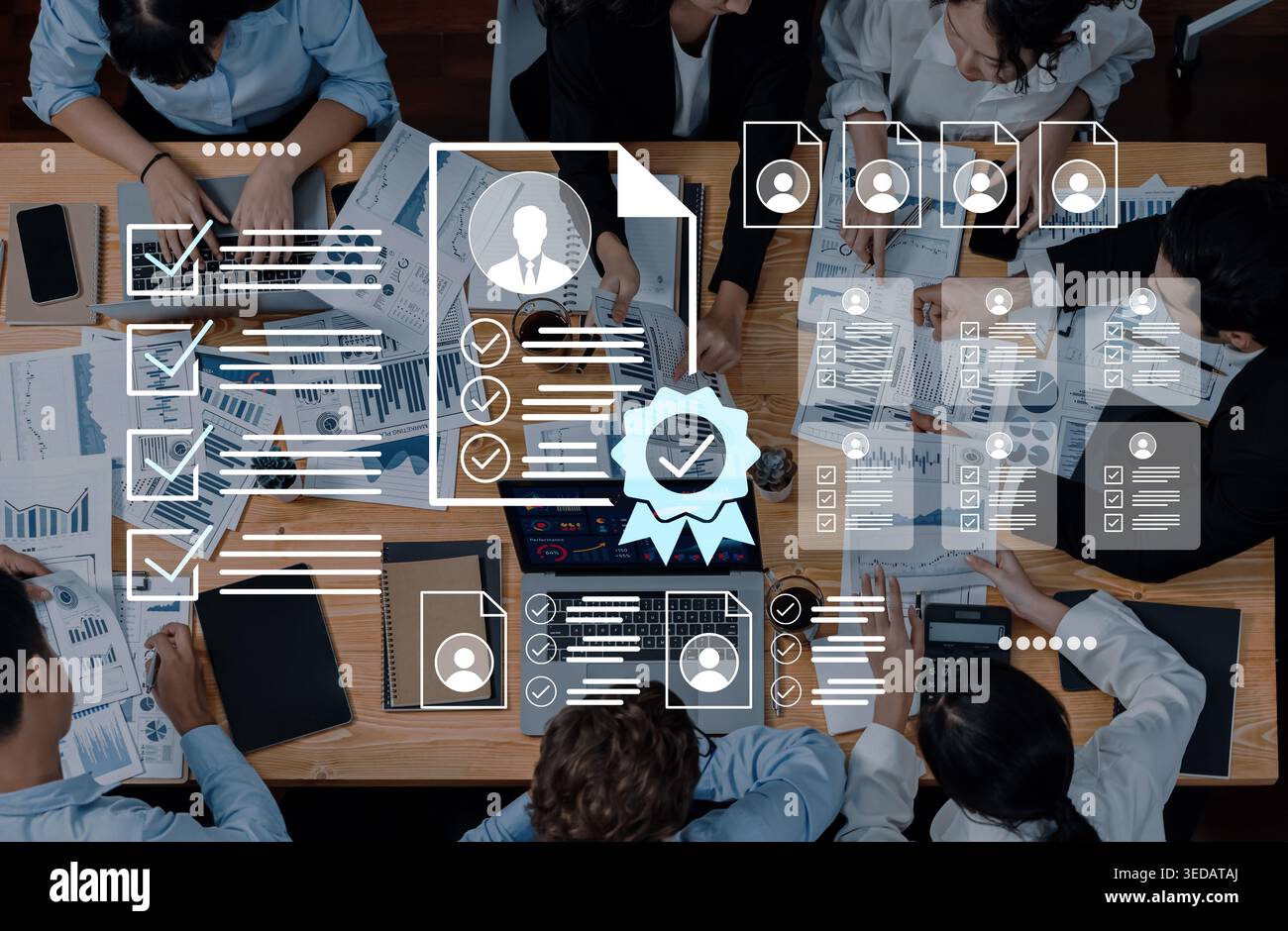 Un team aziendale diversificato collabora attorno a una tabella piena di grafici e documenti, utilizzando la tecnologia per una pianificazione strategica efficace e. Foto Stock