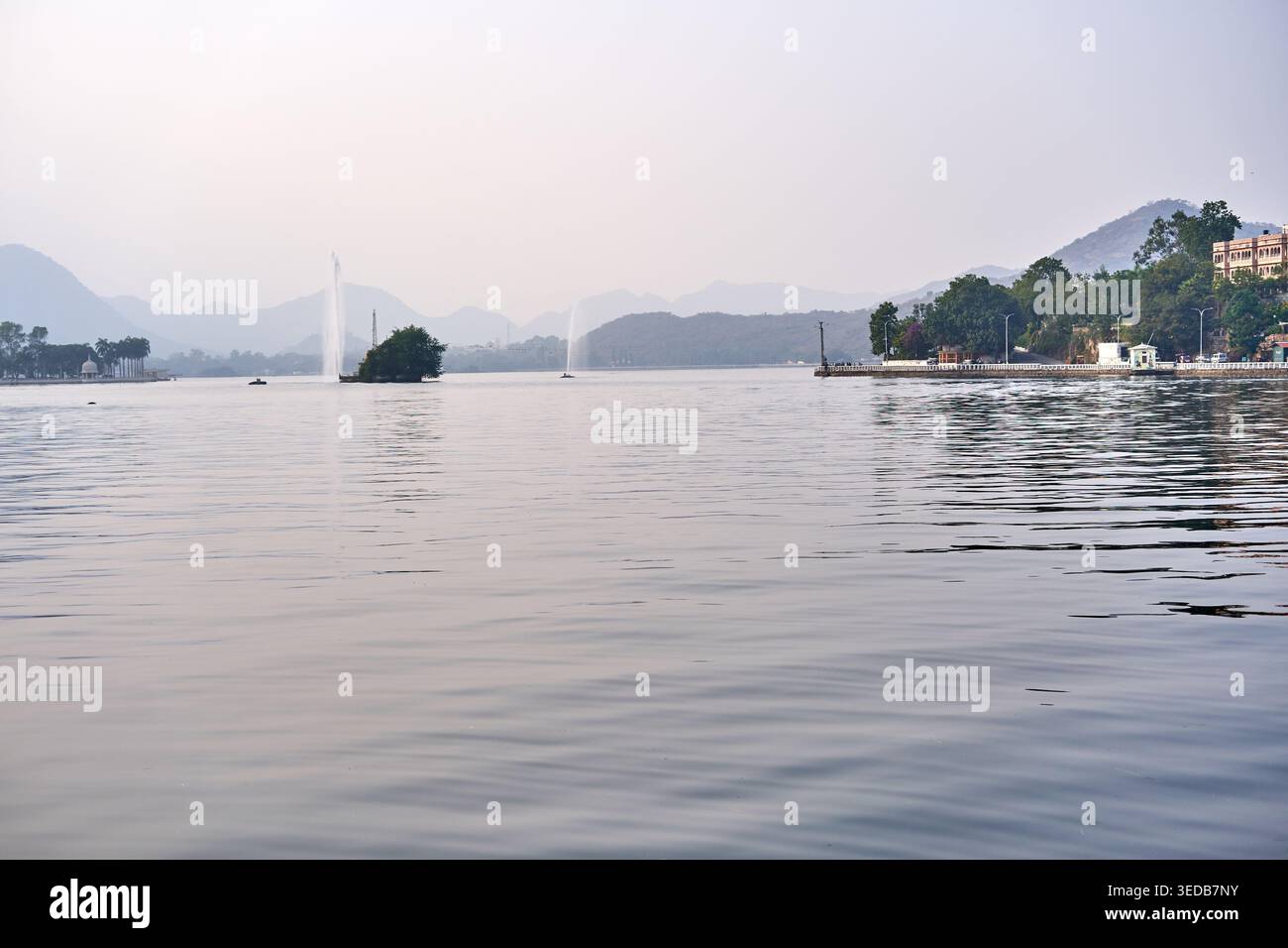 Una vista panoramica serena di un grande lago di acqua dolce con acque calme che si estendono nello sfondo. A media distanza, alte fontane verticali Foto Stock