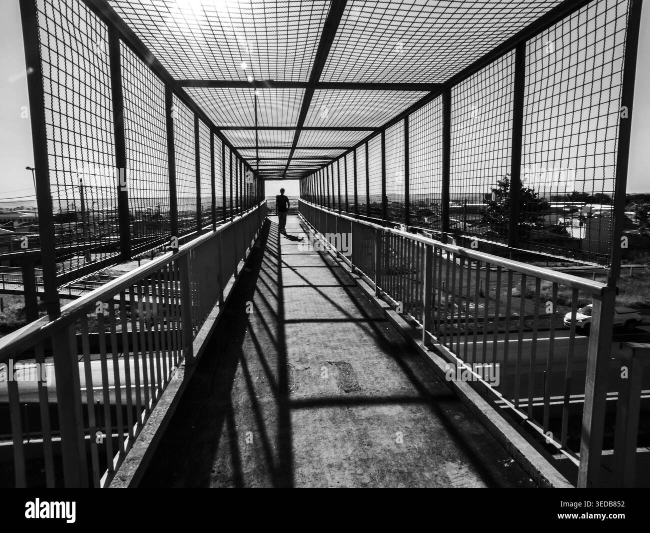 Marilia, SP, Brasile. 4 maggio 2026; vista in bianco e nero di un ponte pedonale su un'autostrada. Una figura solitaria entra nelle linee di prospettiva come t Foto Stock