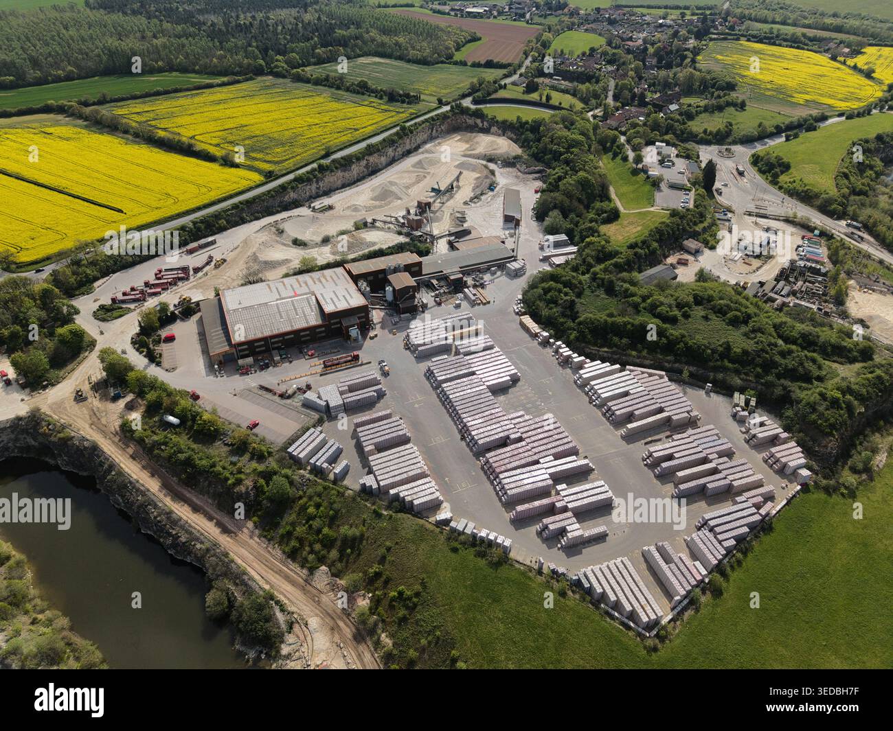 Veduta aerea del sito industriale di Marshalls Maltby, caratterizzato da pile di blocchi di cemento ed edifici industriali circondati da vibranti campi di colza gialli Foto Stock