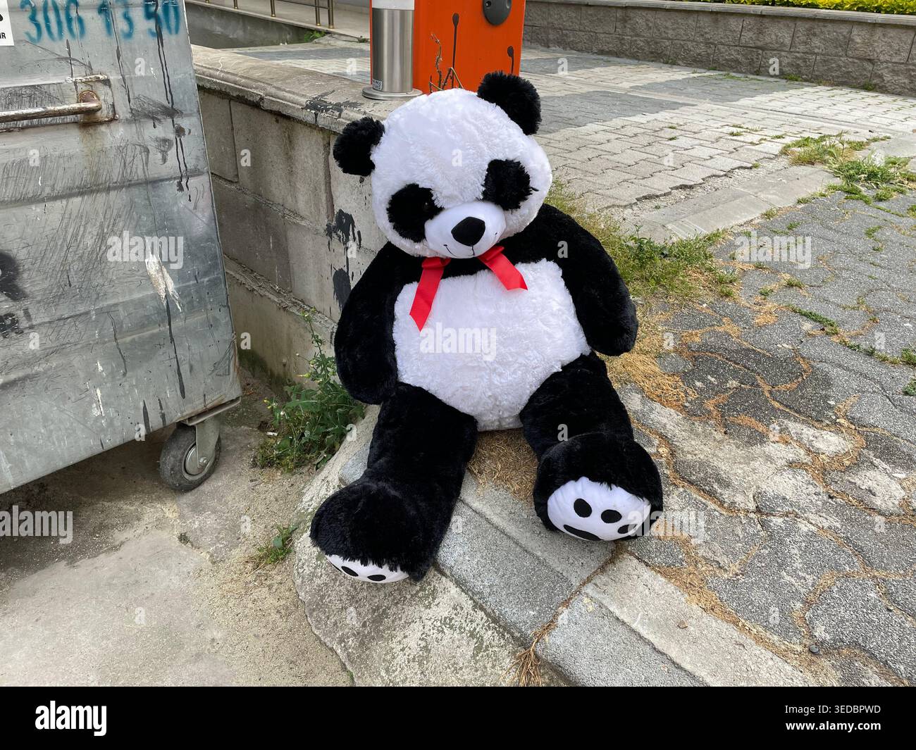 Peluche di panda bianco e nero collocato su un marciapiede della città vicino alla strada, abbandono, infanzia. Foto Stock