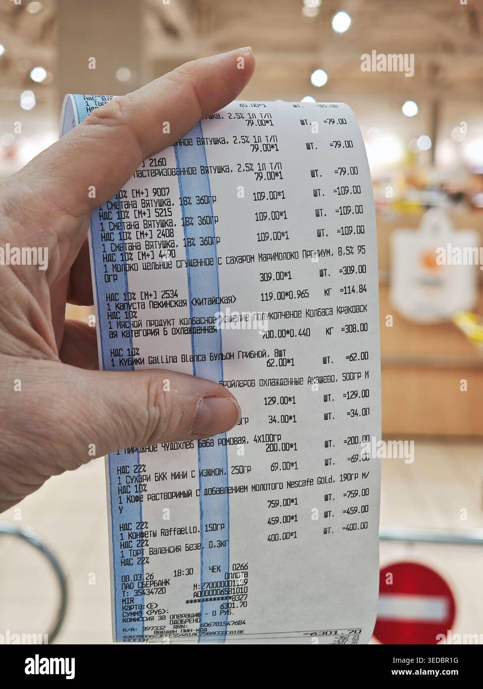 Kirov, Russia - 8 marzo 2026: Hand contiene una ricevuta del negozio che mostra i vari articoli acquistati, i dettagli del pagamento totale e conferma un recente acquisto di generi alimentari Foto Stock