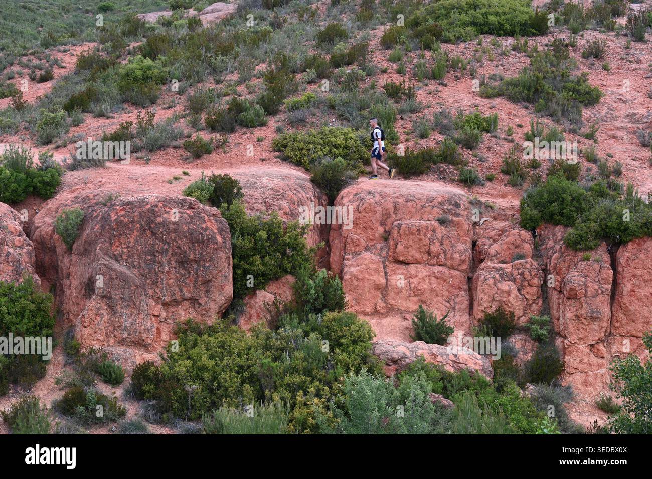 Lone Runner o Single male Cross Country Runner o Jogger che corrono attraverso un paesaggio spettacolare o la campagna di rocce o massi di arenaria Foto Stock